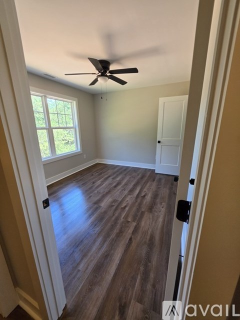 A room with a ceiling fan and wooden flooring.