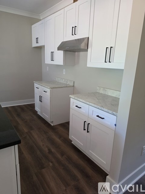 A kitchen with white cabinets and a black counter.