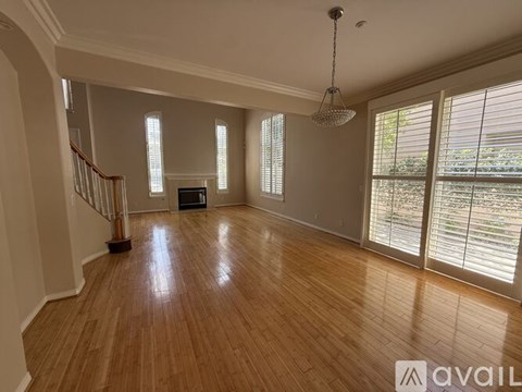 A spacious room with wooden floors and a chandelier.