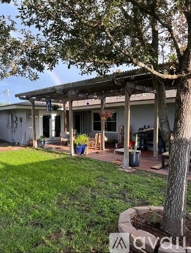 A house with a covered patio and a tree in front.