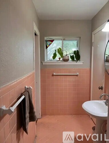 A bathroom with pink tiles and a white sink.