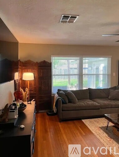 A living room with a grey couch and a wooden floor.