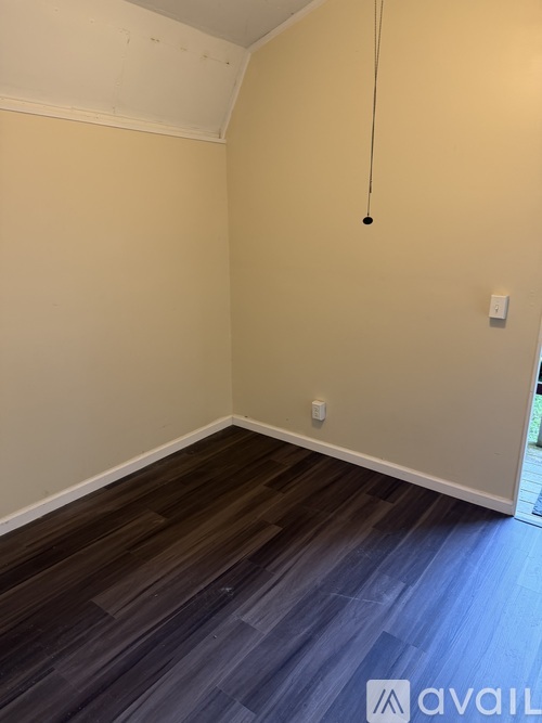 A room with a light brown wall and a dark wood floor.