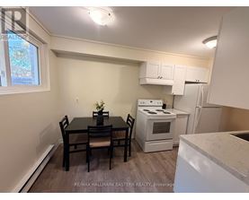 A kitchen with a table and chairs in the foreground and a refrigerator, oven, and microwave in the background.