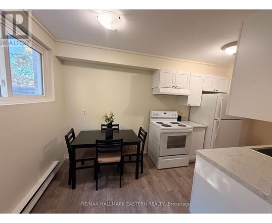 A kitchen with a table and chairs in the foreground and a refrigerator, oven, and microwave in the background.