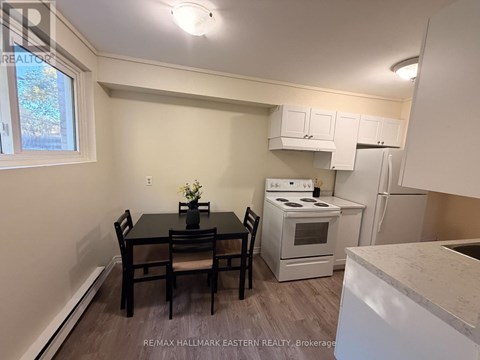 A kitchen with a table and chairs in the foreground and a refrigerator, oven, and microwave in the background.