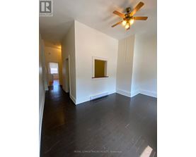 A room with a ceiling fan and wooden floors.