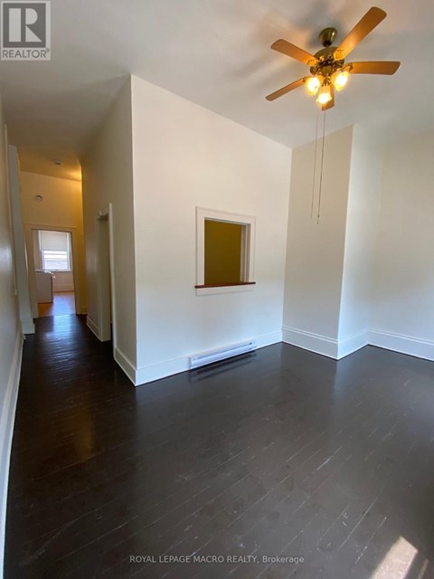 A room with a ceiling fan and wooden floors.