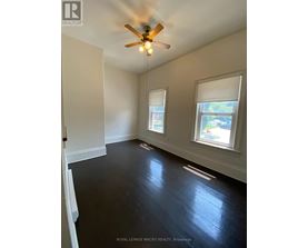 A room with a ceiling fan and two windows.