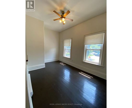 A room with a ceiling fan and two windows.