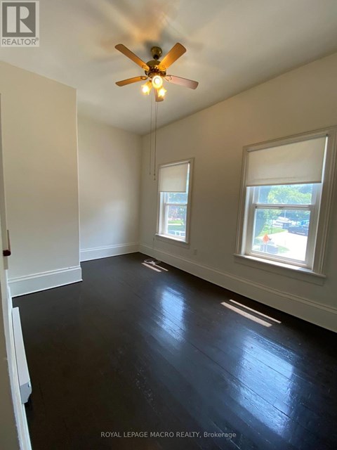 A room with a ceiling fan and two windows.