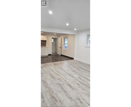 A spacious room with wooden flooring and white walls.