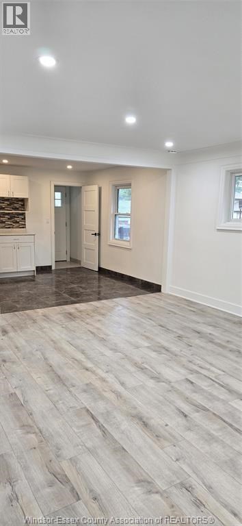 A spacious room with wooden flooring and white walls.