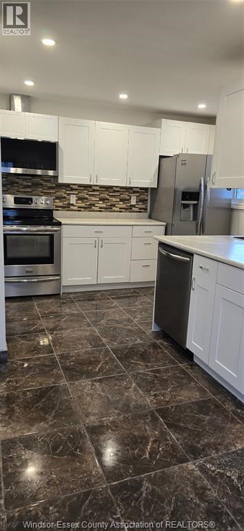 A kitchen with white cabinets and a black stove top oven.