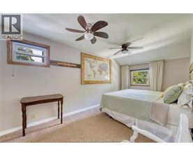 A bedroom with a bed, a table, and a ceiling fan.