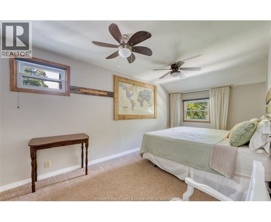 A bedroom with a bed, a table, and a ceiling fan.