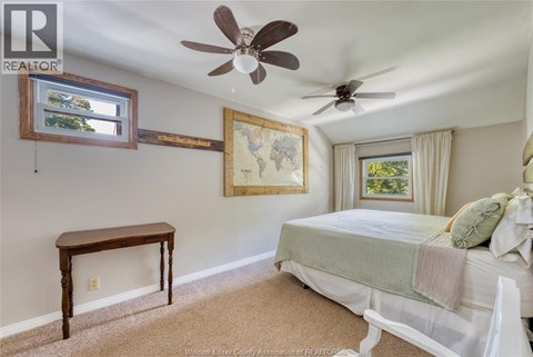 A bedroom with a bed, a table, and a ceiling fan.