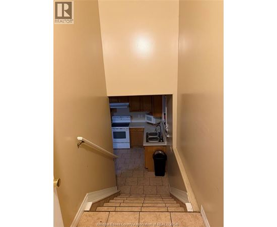 A hallway with a staircase leading to a kitchen.