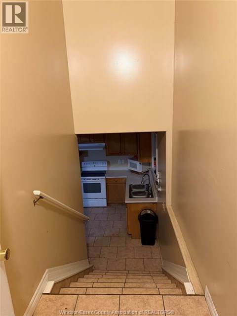 A hallway with a staircase leading to a kitchen.