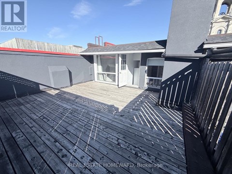 A wooden deck with a railing and a building in the background.