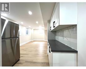 A modern kitchen with a stainless steel refrigerator and wooden flooring.