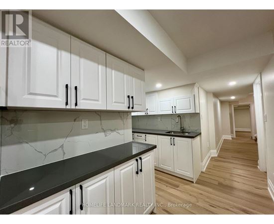 A kitchen with white cabinets and black countertops.