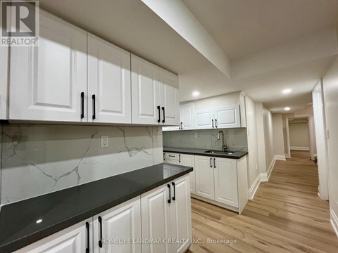 A kitchen with white cabinets and black countertops.