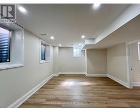 A spacious room with wooden flooring and white walls.