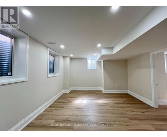 A spacious room with wooden flooring and white walls.