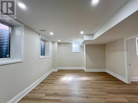 A spacious room with wooden flooring and white walls.