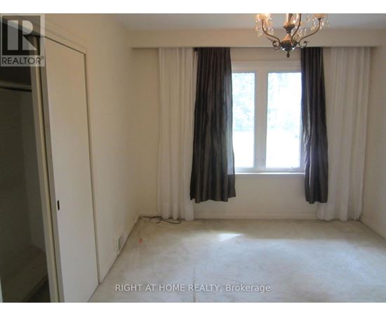 A room with a chandelier, two windows with curtains, and a door.