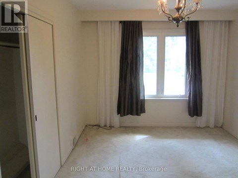 A room with a chandelier, two windows with curtains, and a door.