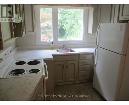 A kitchen with a white fridge, stove and sink.