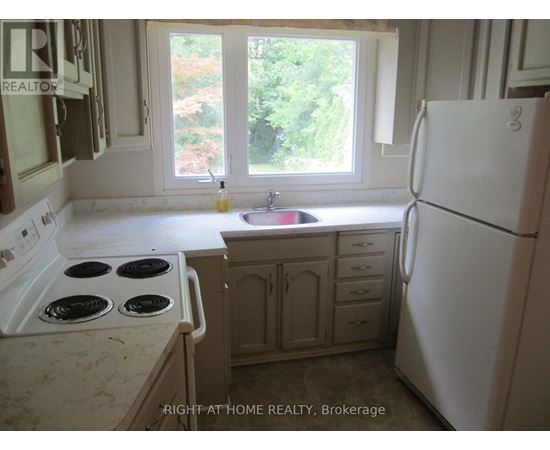 A kitchen with a white fridge, stove and sink.