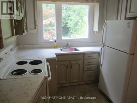 A kitchen with a white fridge, stove and sink.
