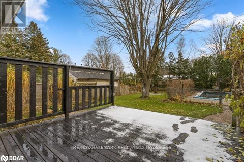 A deck with a railing and a pool in the backyard.