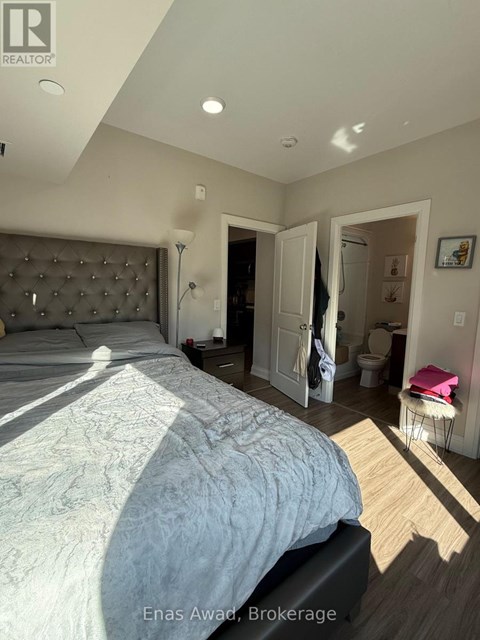 A bedroom with a large bed and a wooden floor.