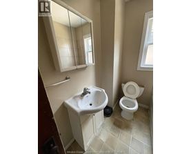 A bathroom with a toilet, sink, and mirror.