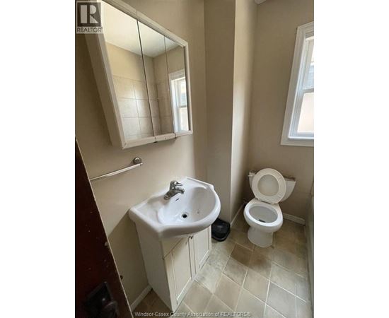 A bathroom with a toilet, sink, and mirror.