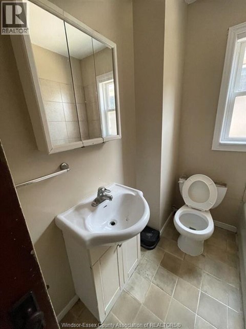 A bathroom with a toilet, sink, and mirror.