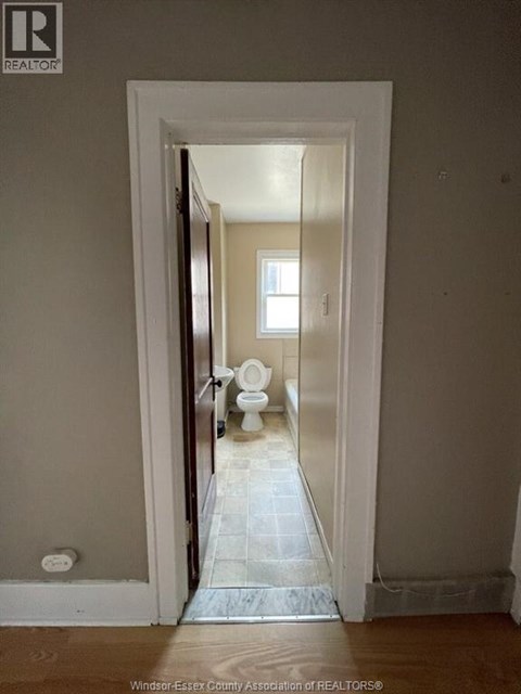 A bathroom with a toilet and a doorway leading to another room.