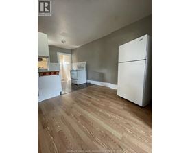 A kitchen with a white fridge and wooden floors.