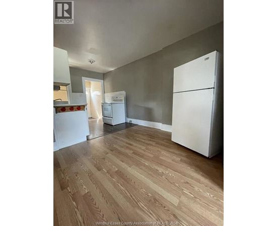 A kitchen with a white fridge and wooden floors.