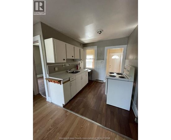 A kitchen with white cabinets and a wooden floor.