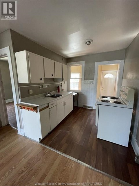 A kitchen with white cabinets and a wooden floor.