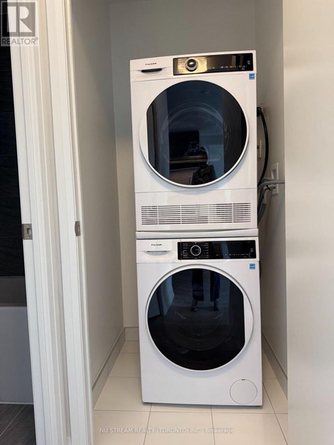A white front loading washing machine with a black door is stacked on top of a smaller white front loading washing machine with a black door.
