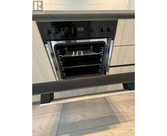 A modern oven with a digital display and control panel is built into a kitchen countertop.