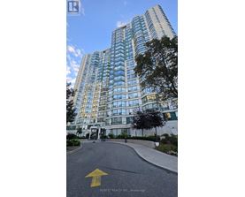A tall building with many windows is shown with a yellow arrow on the road in front.