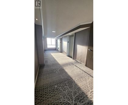A long hallway with carpeted floors and doors on both sides.