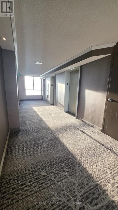 A long hallway with carpeted floors and doors on both sides.